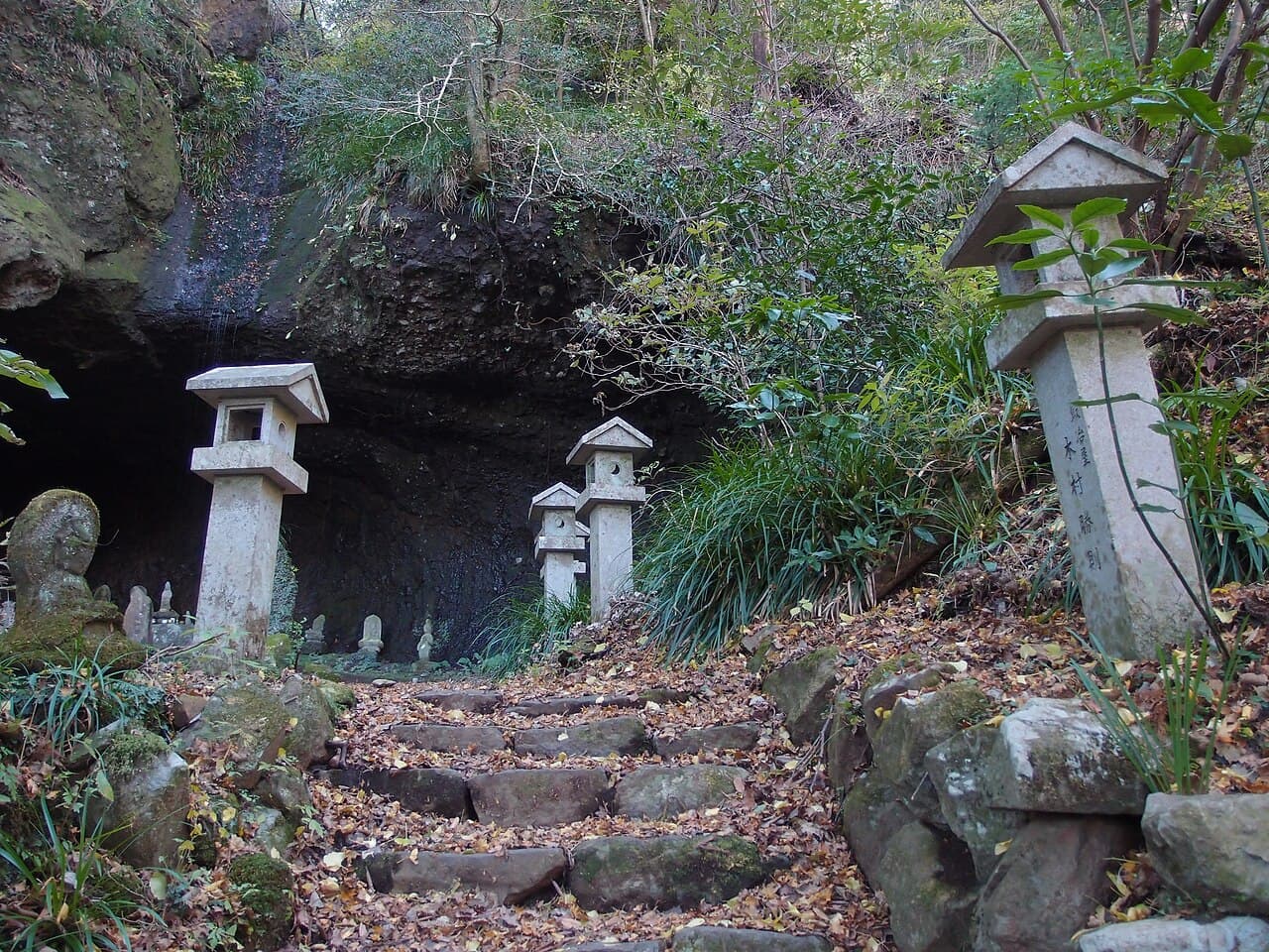 Stone lanterns and Buddhist figures at the entrance to Shitodo Cave.