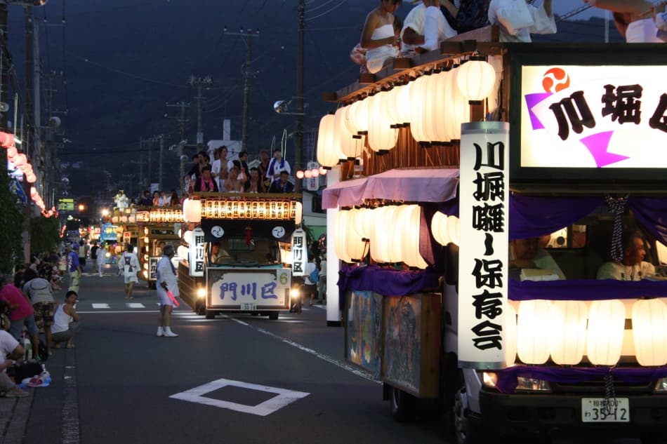提灯を灯した花車が湯河原の通りを進む、やっさまつりの夜のパレード