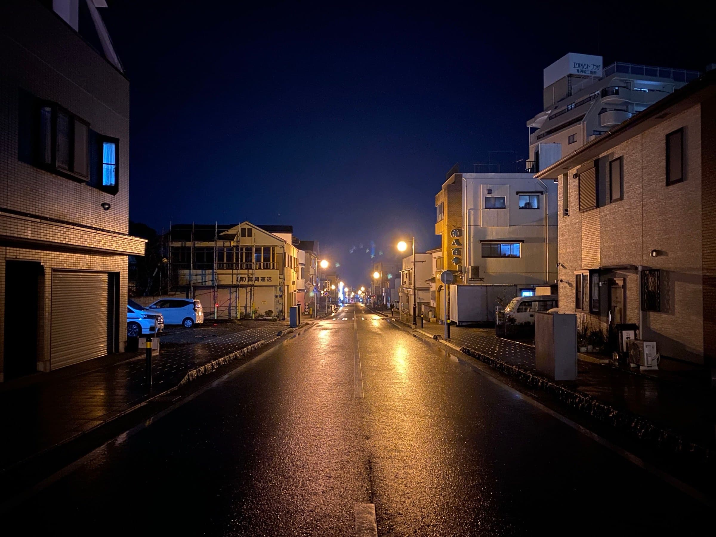 Wet Yugawara street at night, streetlights reflecting on damp pavement
