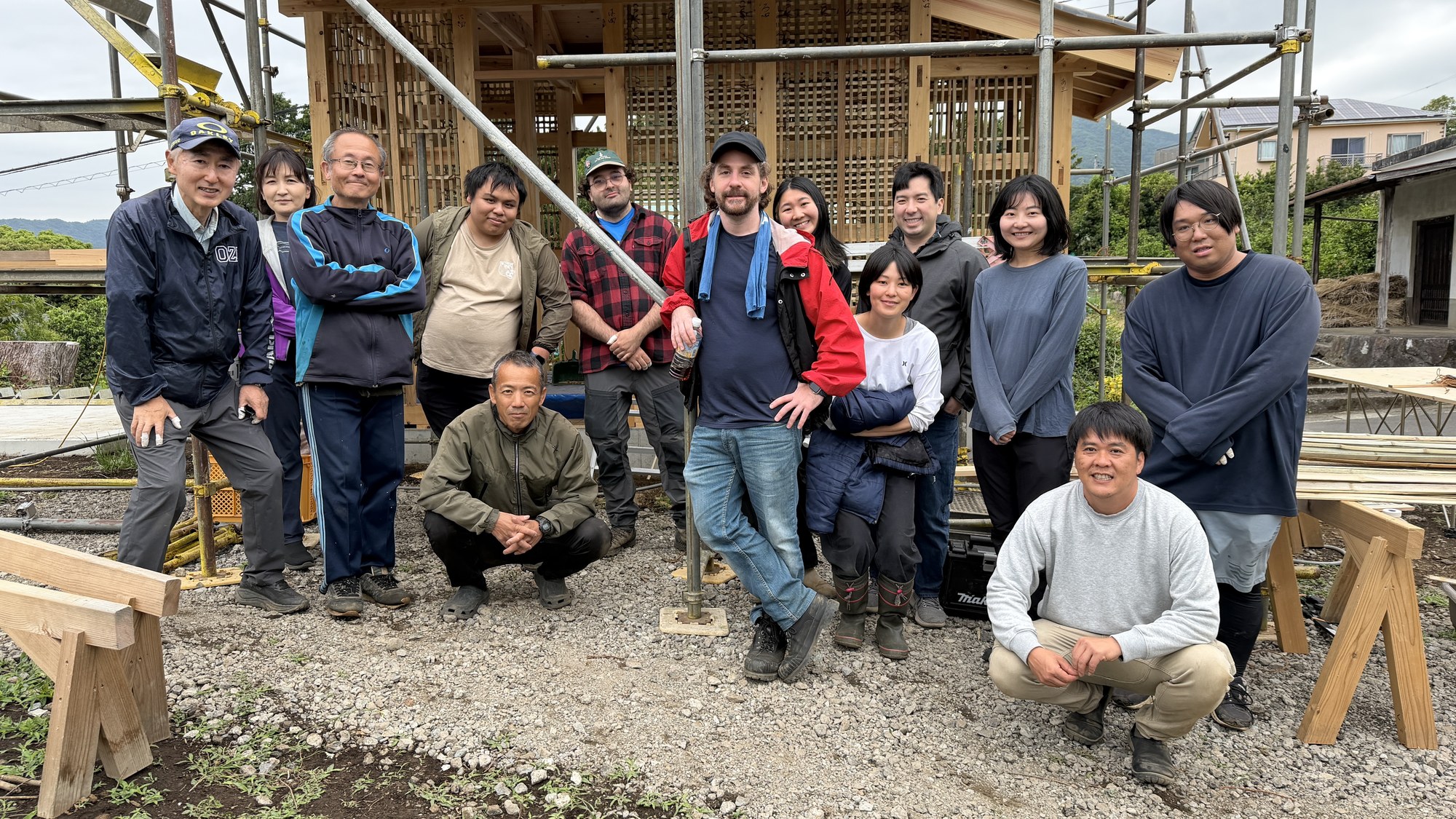 Members and friends of Yugawara Yume Farm gathered beside a timber farm structure