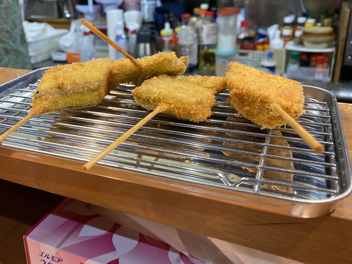 Freshly fried kushiage skewers on a rack at Kinsanchi