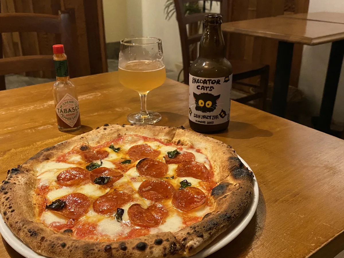 サルーテの木のテーブルに置かれたピザとビール