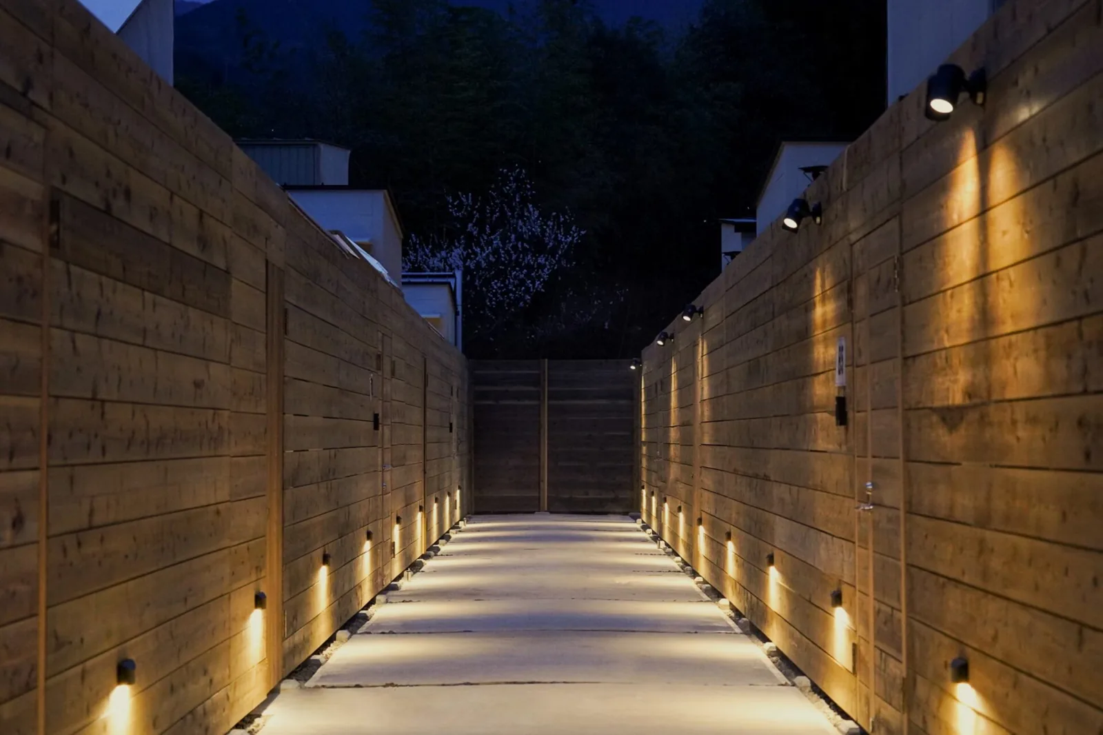 A lantern-lit path between the walled cabins