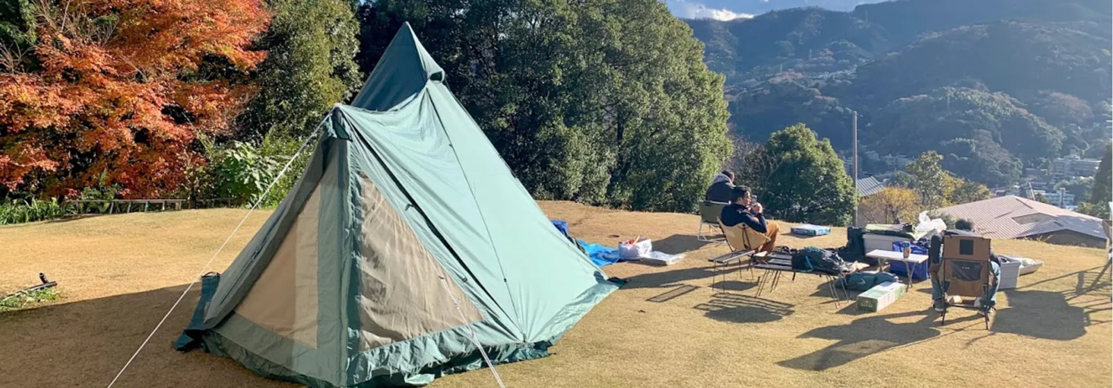 A tent on the grass with the hills of Yugawara behind